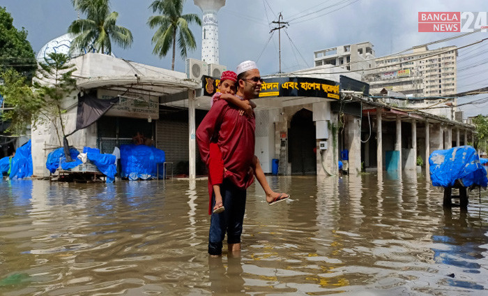 রাজধানীর সড়কে জমেছে পানি। ছেলেকে কাঁধে নিয়ে জুমা শেষে বাড়ি ফিরছেন একজন এক ব্যক্তি। ছবি তুলেছেন শাকিল আহমেদ