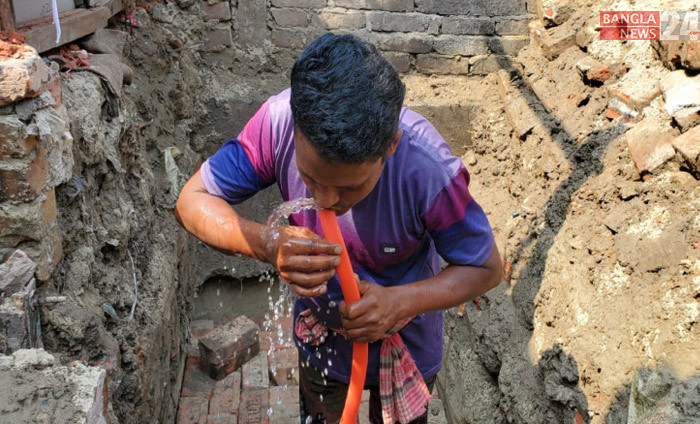 তীব্র গরমে পাইপ দিয়ে পানি পান করছেন নির্মাণ শ্রমিক। ছবি: শাকিল আহমেদ