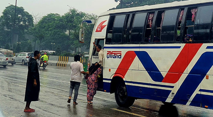 বৃষ্টিভেজা রাস্তা থেকে বাসে উঠছেন এক নারী/ছবি: জি এম মুজিবুর